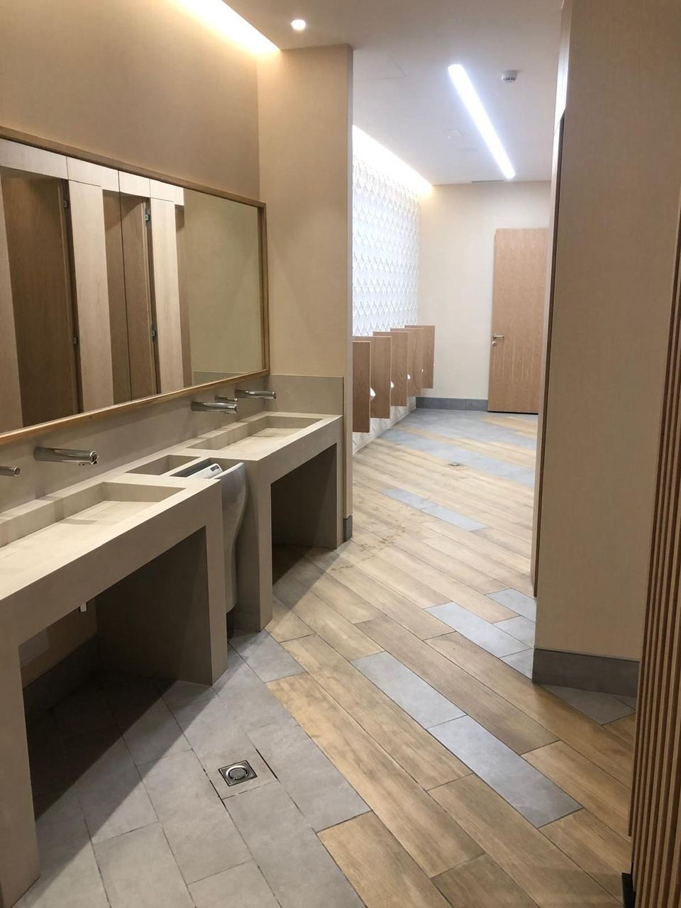 Baño público de local comercial con lavabos de obra y grifería electrónica