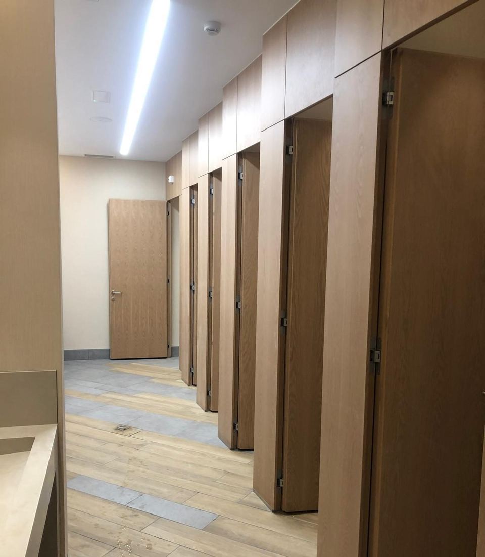 Pasillo de cabinas con puertas de madera y suelo porcelánico