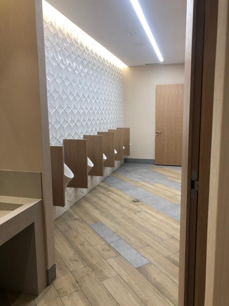 Zona de urinarios con pared de azulejo 3D e iluminación indirecta